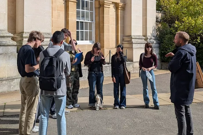 Students listening to a tutor outside a building in Oxford