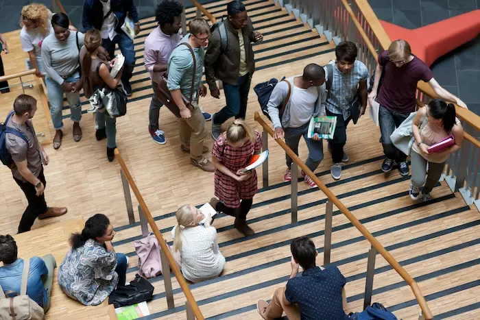 University students sitting on and walking up a wide staircase