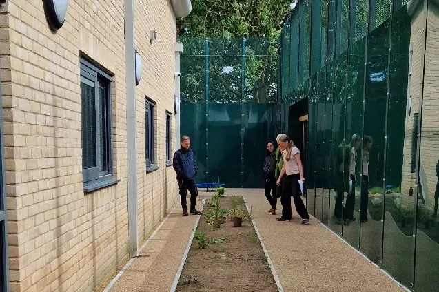 Team members in part of the garden area, empty before planting.