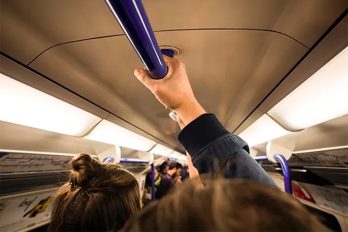 A passenger holds an overhead rail in a tube carriage