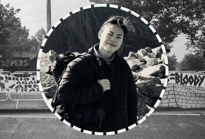 Dr Yung Au; background is banners against the arms trade, taken during her research (c) Yung Au with permission.
