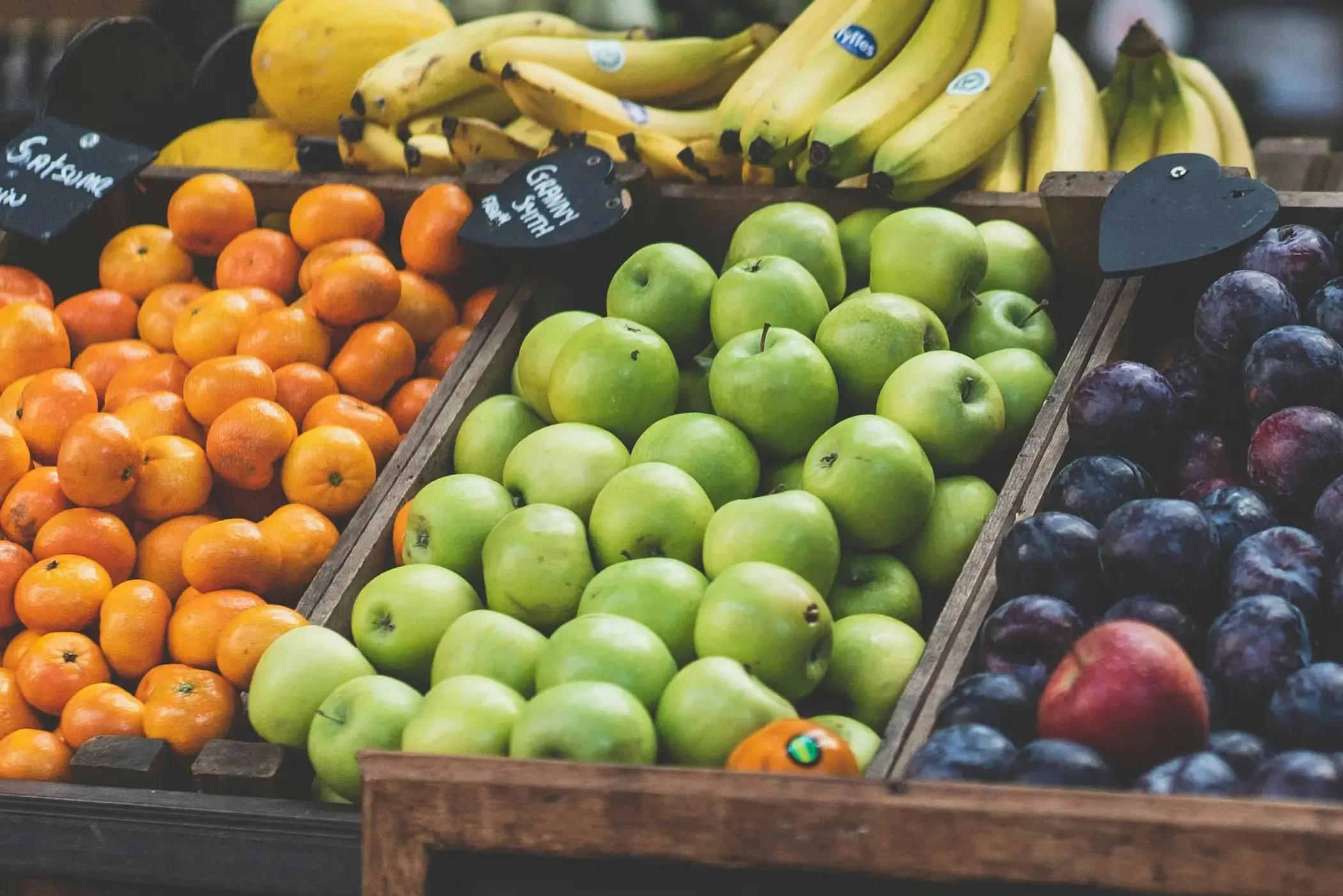 Oranges, green apples, plums and bananas on a market stall